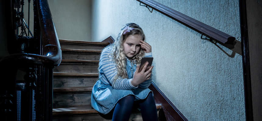 article photo of a stressed out child sitting staring at phone while sitting on stairs by Dr. Sam Goldstein