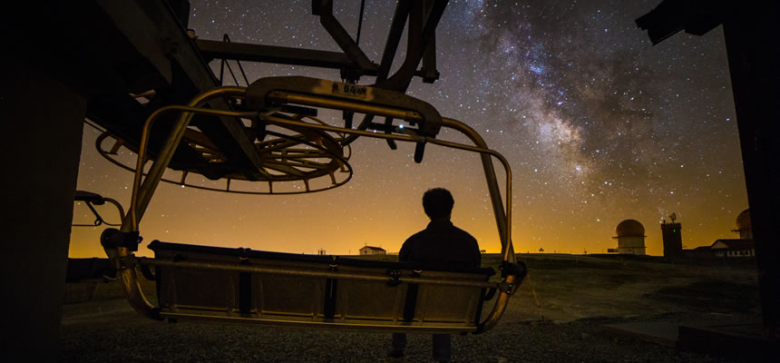 article photo of a man sitting on ski lift beneath night sky stars pondering what makes us human. by Dr. Sam Goldstein